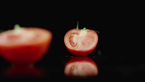 Jugoso-Tomate-Rojo-En-Rodajas-Cae-En-2-Partes-De-Vidrio-Con-Salpicaduras-De-Agua-En-Cámara-Lenta-Sobre-Un-Fondo-Oscuro